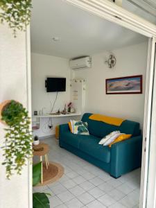 a living room with a blue couch and a tv at La Kawannaise Blue Lagon - Piscine, Wifi, Plage, Terrasse in Grand-Bourg