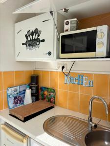 a kitchen counter with a sink and a microwave at La Kawannaise Blue Lagon - Piscine, Wifi, Plage, Terrasse in Grand-Bourg +21 photos