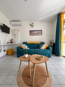 a living room with a blue couch and a table at La Kawannaise Blue Lagon - Piscine, Wifi, Plage, Terrasse in Grand-Bourg