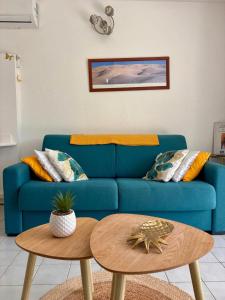 a living room with a blue couch and two tables at La Kawannaise Blue Lagon - Piscine, Wifi, Plage, Terrasse in Grand-Bourg