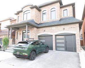 a green car parked in front of a house at New Basement Apartment with parking in Oakville