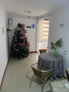 a christmas tree in a room with a table and chairs at Hotel El paraiso Funza in Funza