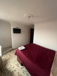 a bedroom with a bed with a red blanket at Hotel El paraiso Funza in Funza