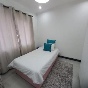 a bedroom with a bed with white sheets and blue pillows at 200 on Genazzano in Densainagar