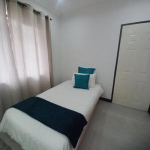 a small bedroom with a bed with blue pillows at 200 on Genazzano in Densainagar +8 photos