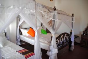 1 dormitorio con cama con dosel y almohadas de color naranja y verde en Miura Dutch Edge Hotel, en Negombo