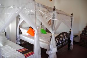 a bedroom with a canopy bed with orange and green pillows at Miura Dutch Edge Hotel in Negombo