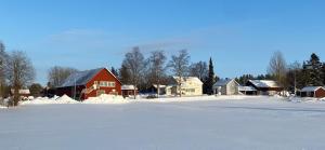 a red barn in the snow next to houses at Charmig stuga på bondgård in Norrfjärden