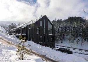 a cabin in the snow with a car parked next to it at JASNÁ Luxury Apartments with Mountain View in Belá