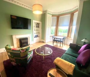 a living room with a green couch and a fireplace at Ochil View in Stirling