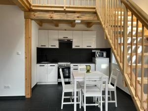 a kitchen with white cabinets and a table and chairs at Jolcsi Apartman in Balatonfüred