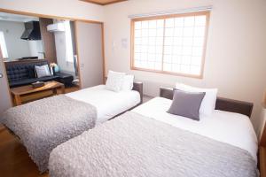 two beds in a small room with a window at Guest House Nishimiyanosawa in Teine