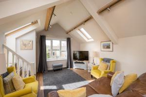 a living room with yellow chairs and a tv at Tanyard Barn - North Yorkshire in York