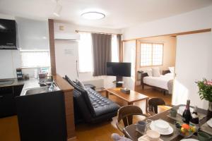 a kitchen and living room with a couch and a table at Guest House Nishimiyanosawa in Teine