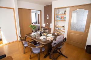 a dining room with a wooden table and chairs at Guest House Nishimiyanosawa in Teine