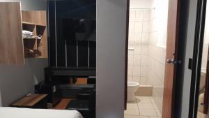 a bedroom with a piano and a bathroom with a toilet at HotelesR20 in Lima