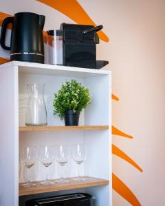 a shelf with wine glasses and a plant on it at Cocon coloré - centre de Caen - tout à pied in Caen +10 photos