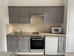 a kitchen with gray cabinets and a sink and a microwave at Self Contained Studio Flat in London +5 photos