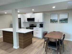 a kitchen with a table and a kitchen with white cabinets at The Basement Suite on Paradise Hill in Prince George