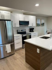 a kitchen with white cabinets and a stainless steel refrigerator at The Basement Suite on Paradise Hill in Prince George +4 photos
