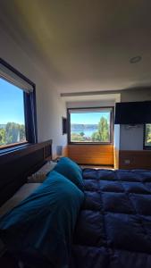 a bedroom with a large bed and two windows at Cabañas y hostal Aurora in Castro