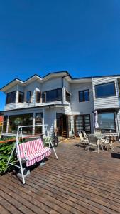 a house with a deck with a bench and chairs at Cabañas y hostal Aurora in Castro