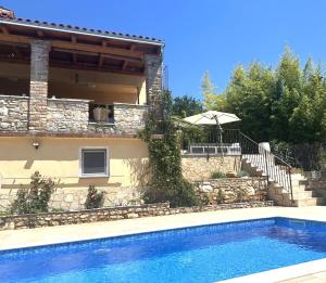 a villa with a swimming pool in front of a house at Villa Doba - Visnjan in Višnjan