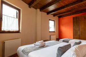 two beds in a room with orange walls and windows at Hotel Nau Iori in Vielha