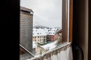 a view of a snowy city from a window at Hotel Nau Iori in Vielha +31 photos