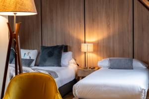 a hotel room with two beds and a yellow chair at Hotel Nau Iori in Vielha