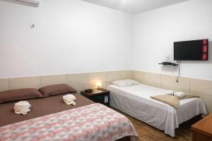 a bedroom with two beds and a flat screen tv at Pousada Areias de Amaro in Santo Amaro