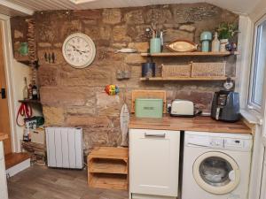a kitchen with a washing machine and a clock on the wall at Corner Cottage in Seahouses