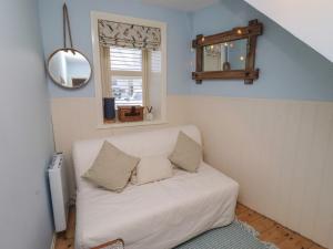 a living room with a white couch and a mirror at Corner Cottage in Seahouses