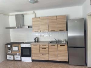a kitchen with wooden cabinets and a stainless steel refrigerator at Chalupa U Revíru in Chvalčov +14 photos
