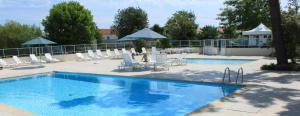a swimming pool with white chairs and umbrellas at La Baie de la tranquilité in Saint-Pierre-dʼOléron