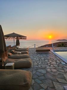 a group of lounge chairs with the sunset in the background at Eternal Blue Kythnos in Mérikhas