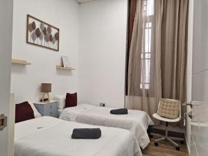 a room with two beds and a chair and a window at The Cathedral Hostel in Murcia