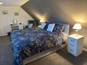 a bedroom with a bed with a blue comforter at Woodlands Banff in Banff