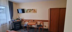 a room with a table and chairs and a television at 2x Einzelbetten - Gästezimmer - 11min von Gießen Zentrum 8,4km in Fernwald in Steinbach
