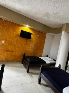 a room with two beds and a flat screen tv at mansion cafetera in Quimbaya