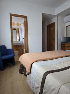 a bedroom with a large bed and a blue chair at Hotel Espada a 174 kilómetros de Santiago de Compostela in A Rúa