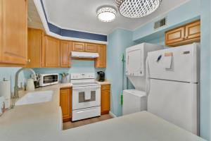 a kitchen with white appliances and wooden cabinets at Fenwick Woods OC in Ocean City +14 photos