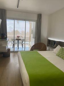a hotel room with a green bed and a table at Diamantchery - Vue mer avec Deck privatif in Le Diamant
