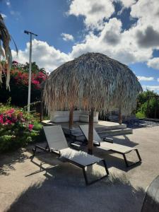 a group of lounge chairs and a grass umbrella at Diamantchery - Vue mer avec Deck privatif in Le Diamant