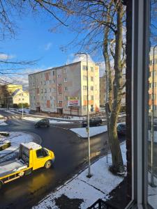 a yellow truck is driving down a city street at Szczecinek apartament in Szczecinek