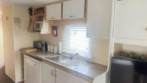 a small kitchen with a sink and a microwave at 10 Berth Caravan - Meadow View in Skegness