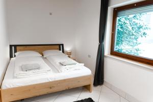 a bedroom with a bed with white sheets and a window at Haus Treff in Weissenbach am Lech