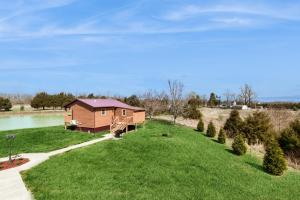 a cabin on a grassy field next to a lake at Pet Friendly! Countryside Couples Stay in Illinois in Etherton