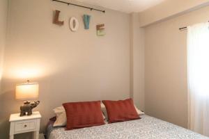 a bedroom with a bed and a table with a lamp at North Shore Bungalow in Mokuleia