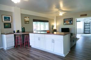 a kitchen with white cabinets and a bar with stools at North Shore Bungalow in Mokuleia